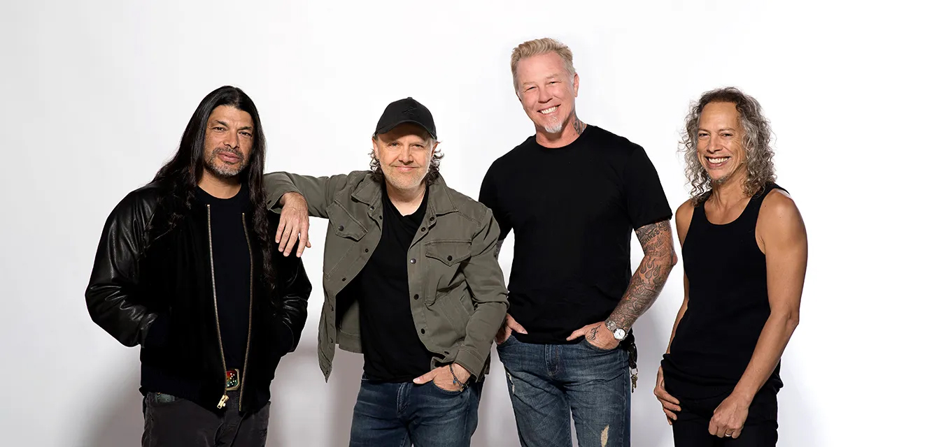 Members of Metallica stand together and smile.