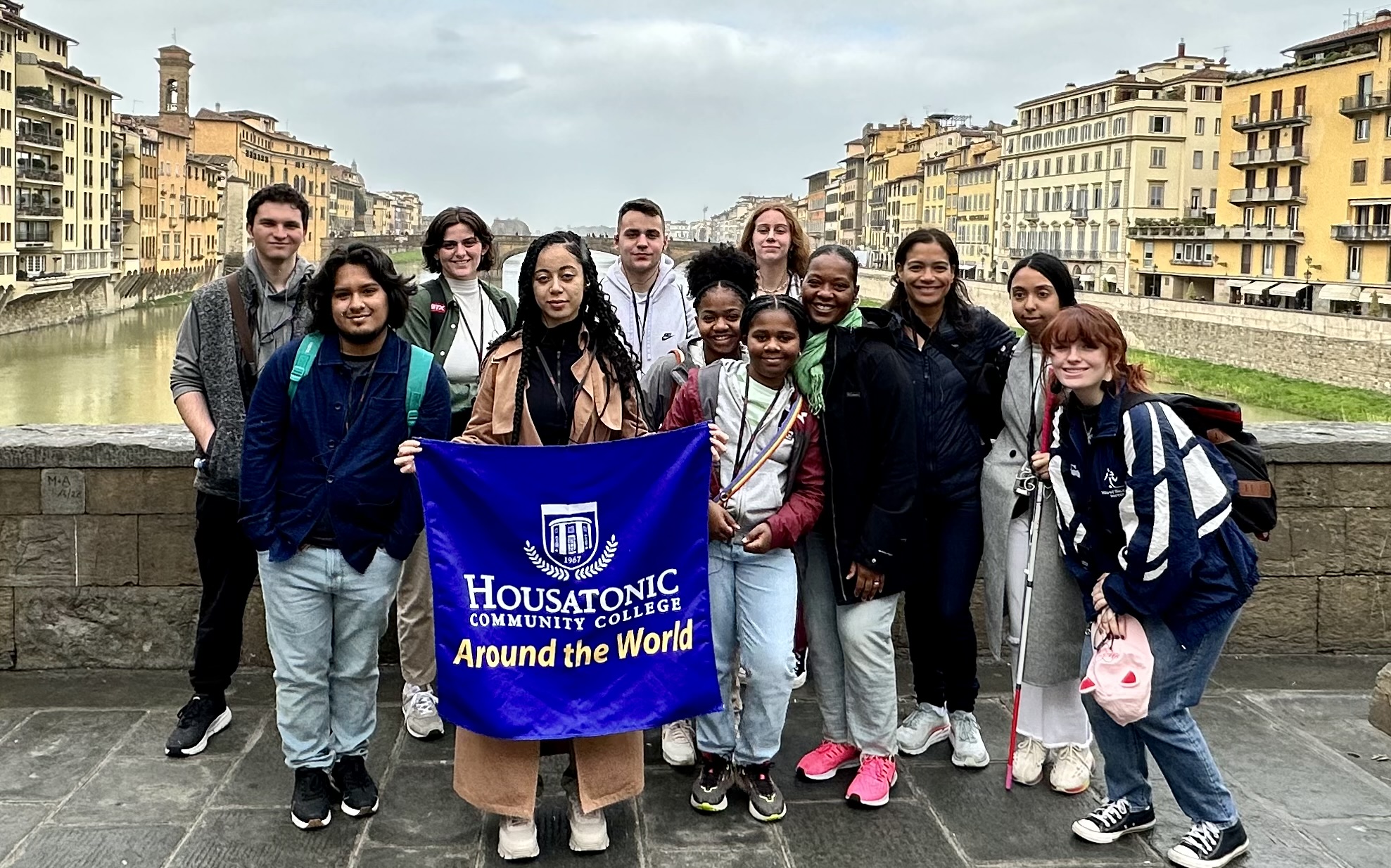Study abroad students stand with Housatonic study abroad flag in European city.