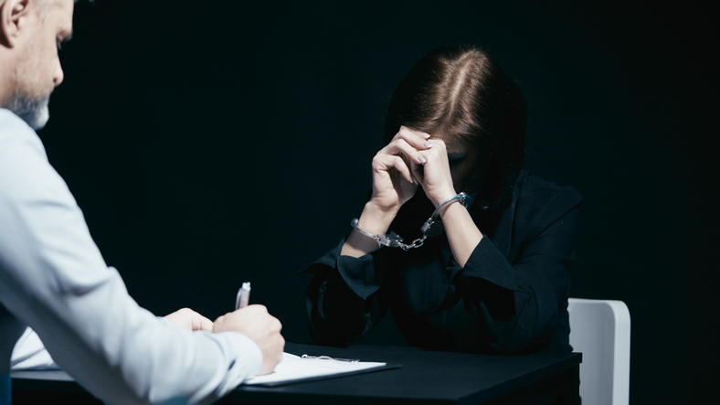 woman in handcuffs looks down with head in hands