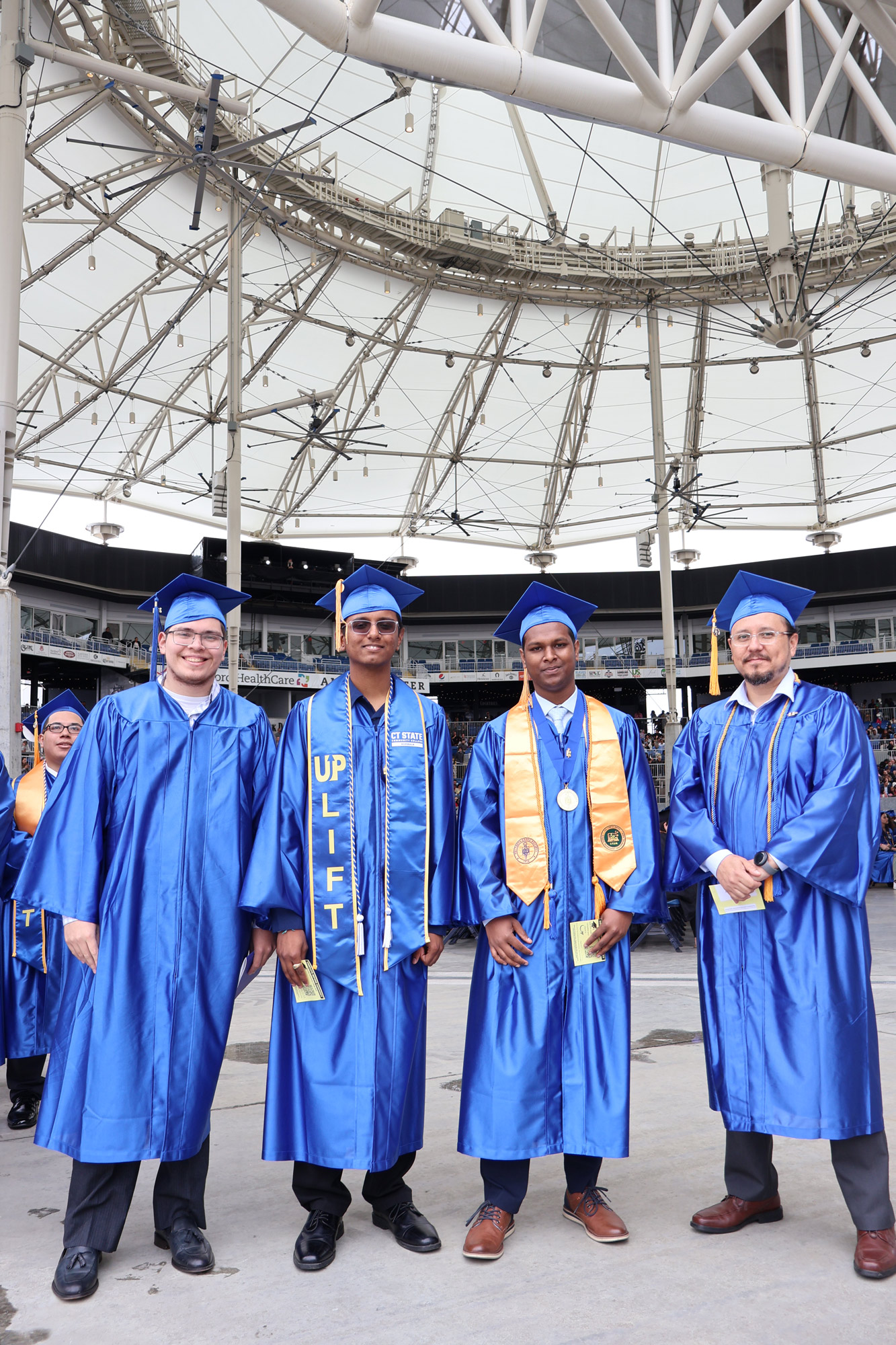 four graduates stand together under dome