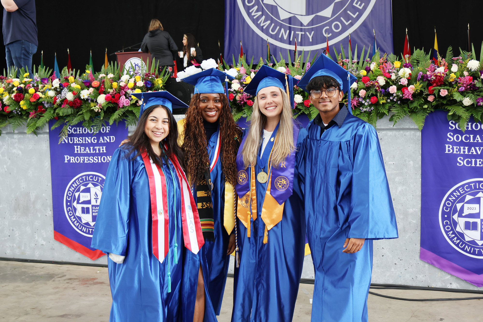 group of 4 smiling graduates in front of stage