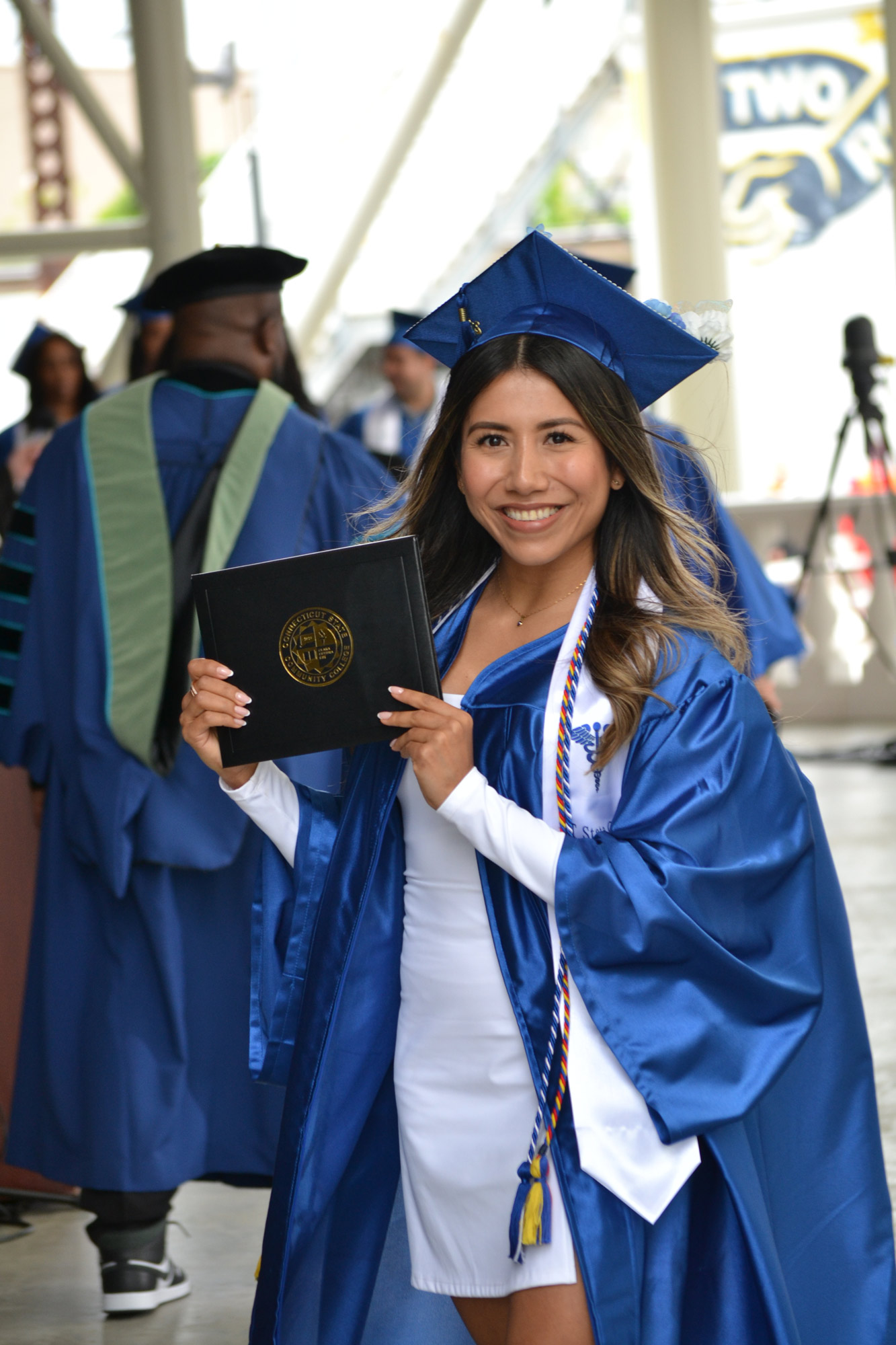smiling female graduate holds up diploma