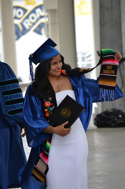graduate holds up scarf that says 