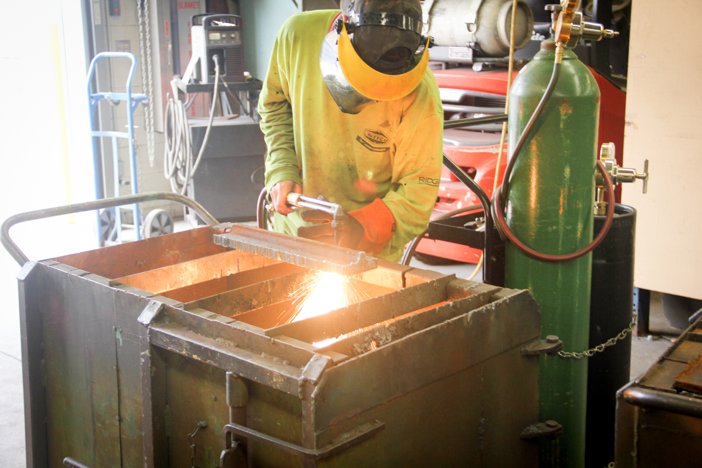 Student welds metal while sparks fly