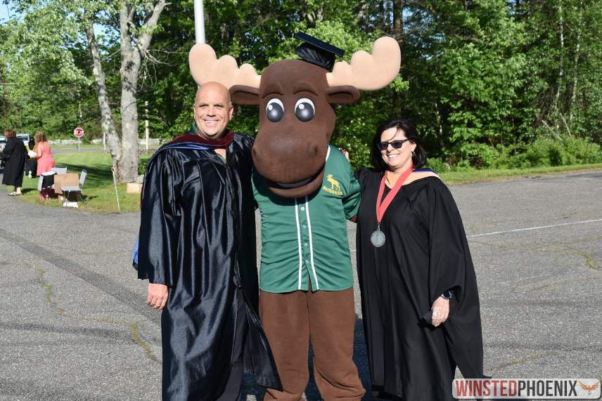 Maddie the moose stands with two graduates