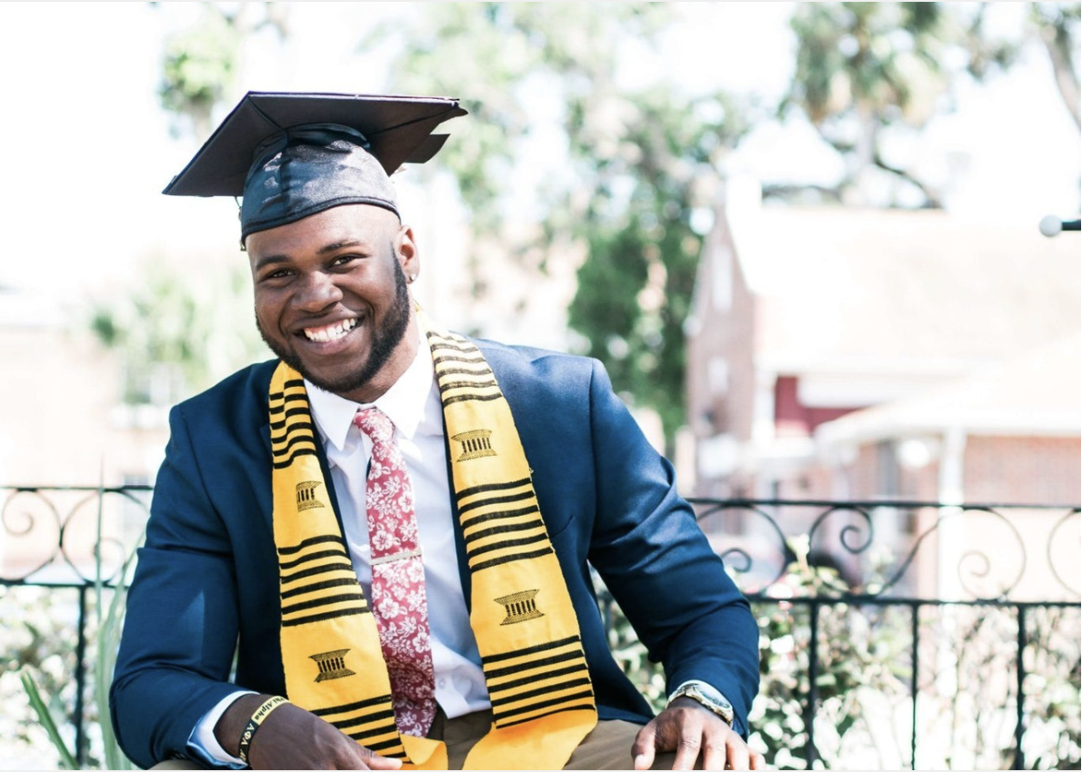 male graduate smiles at camera