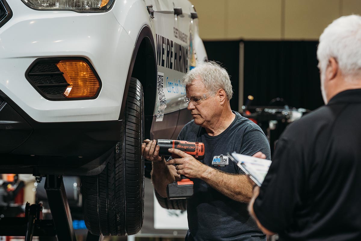 An instructor looking underneath a car