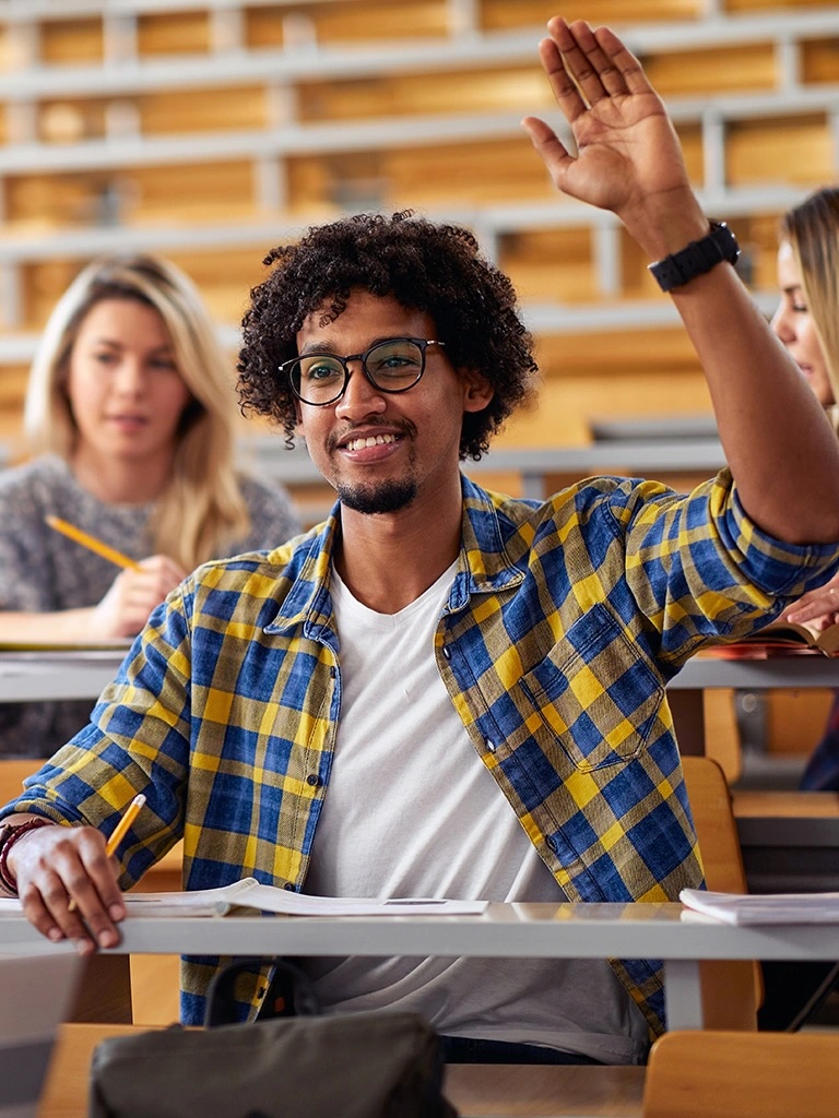 student sitting in lecture hall raises his hand