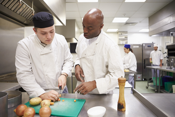 culinary professor teaches student how to cut vegetables