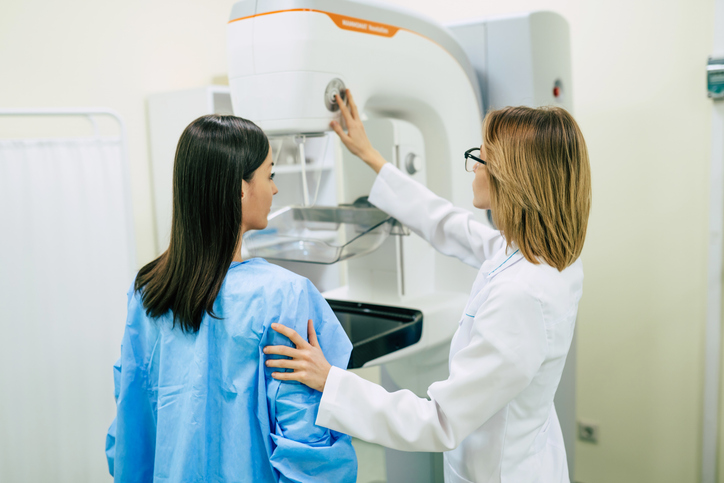 Mammography tech works with patient to take mammogram