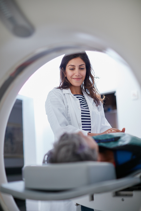 technologist helps patient into MRI machine