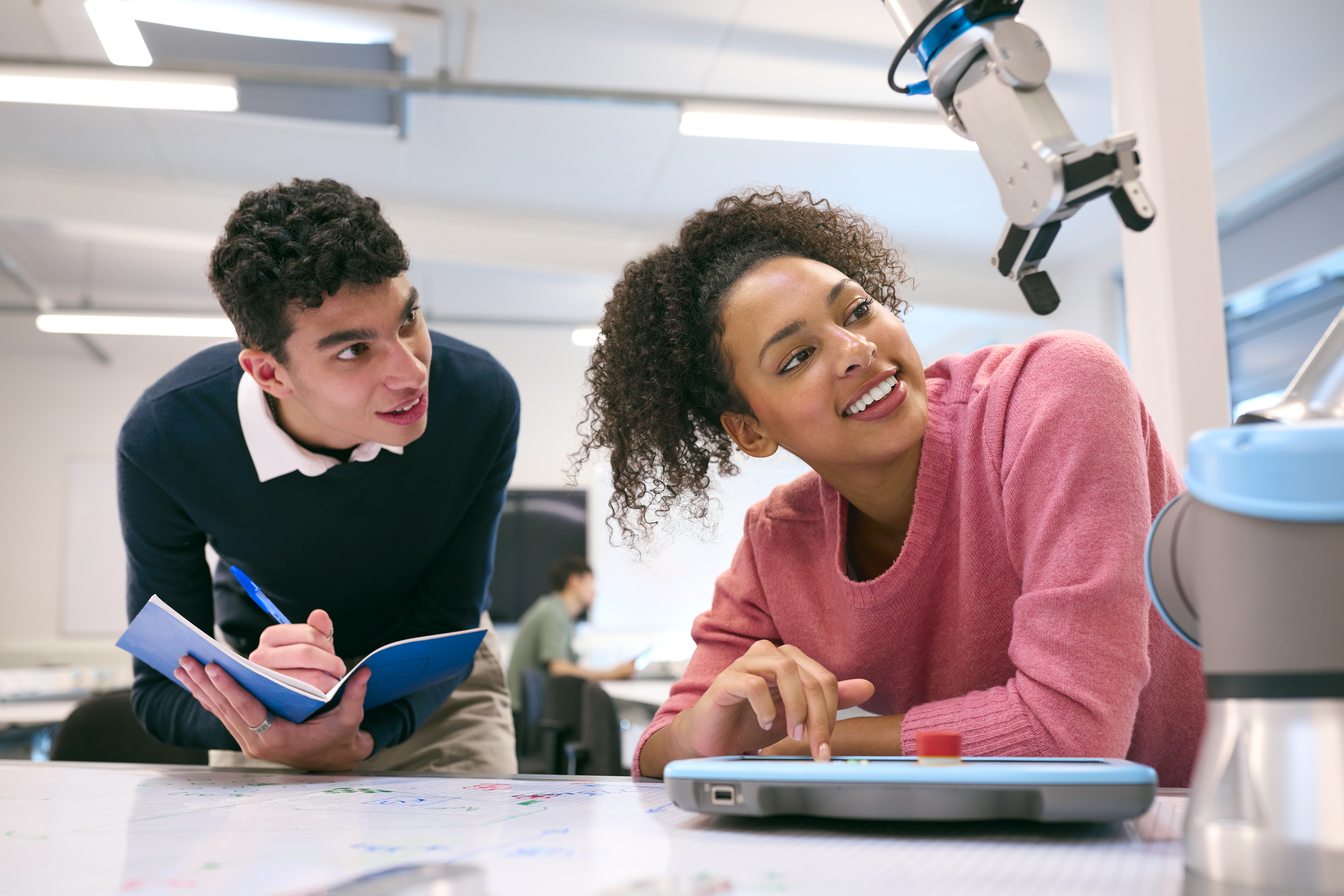 two students work together on robotosMale And Female College Or University Engineering Students In Robotics Class Working Together