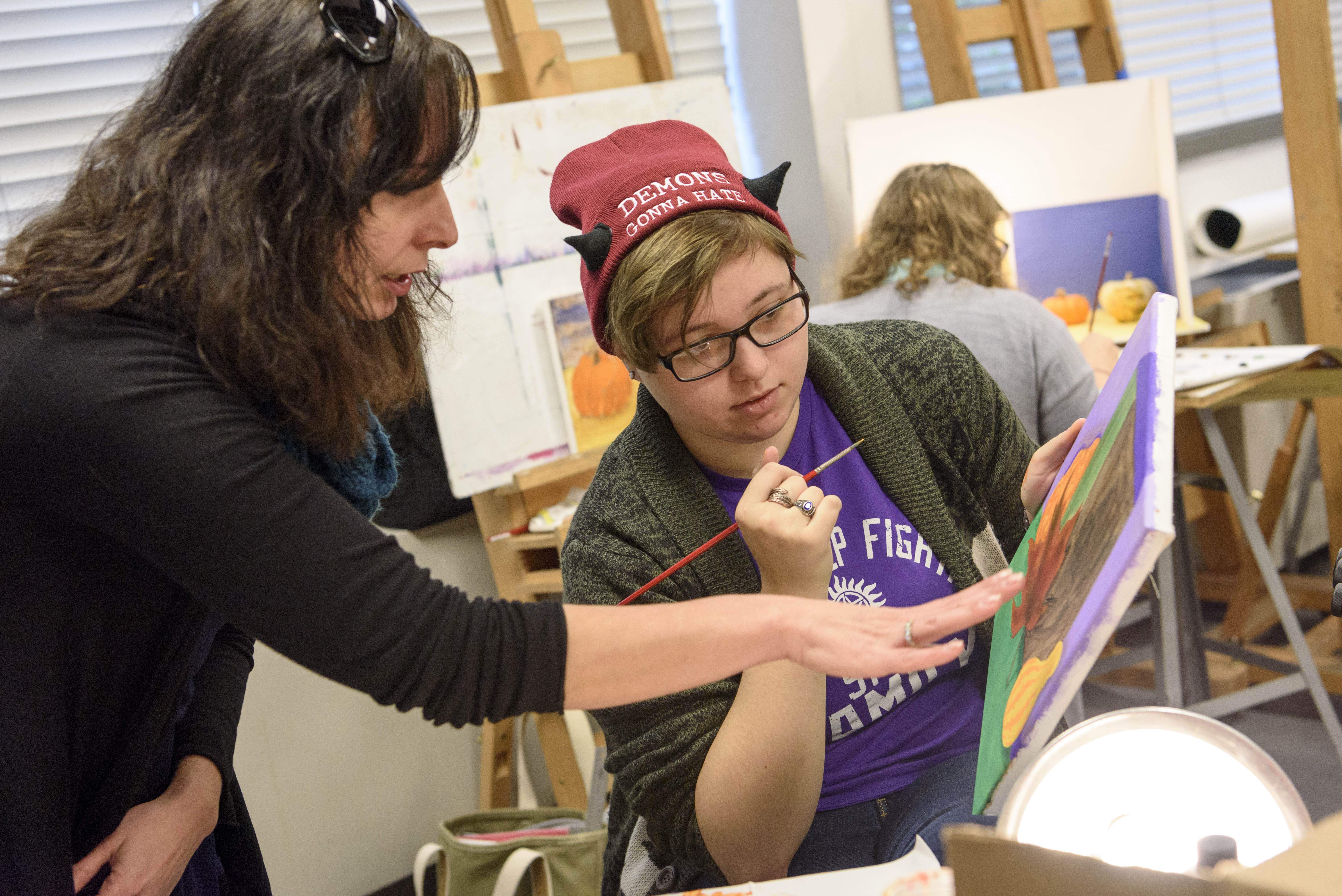 Art professor critiques student painting with student.