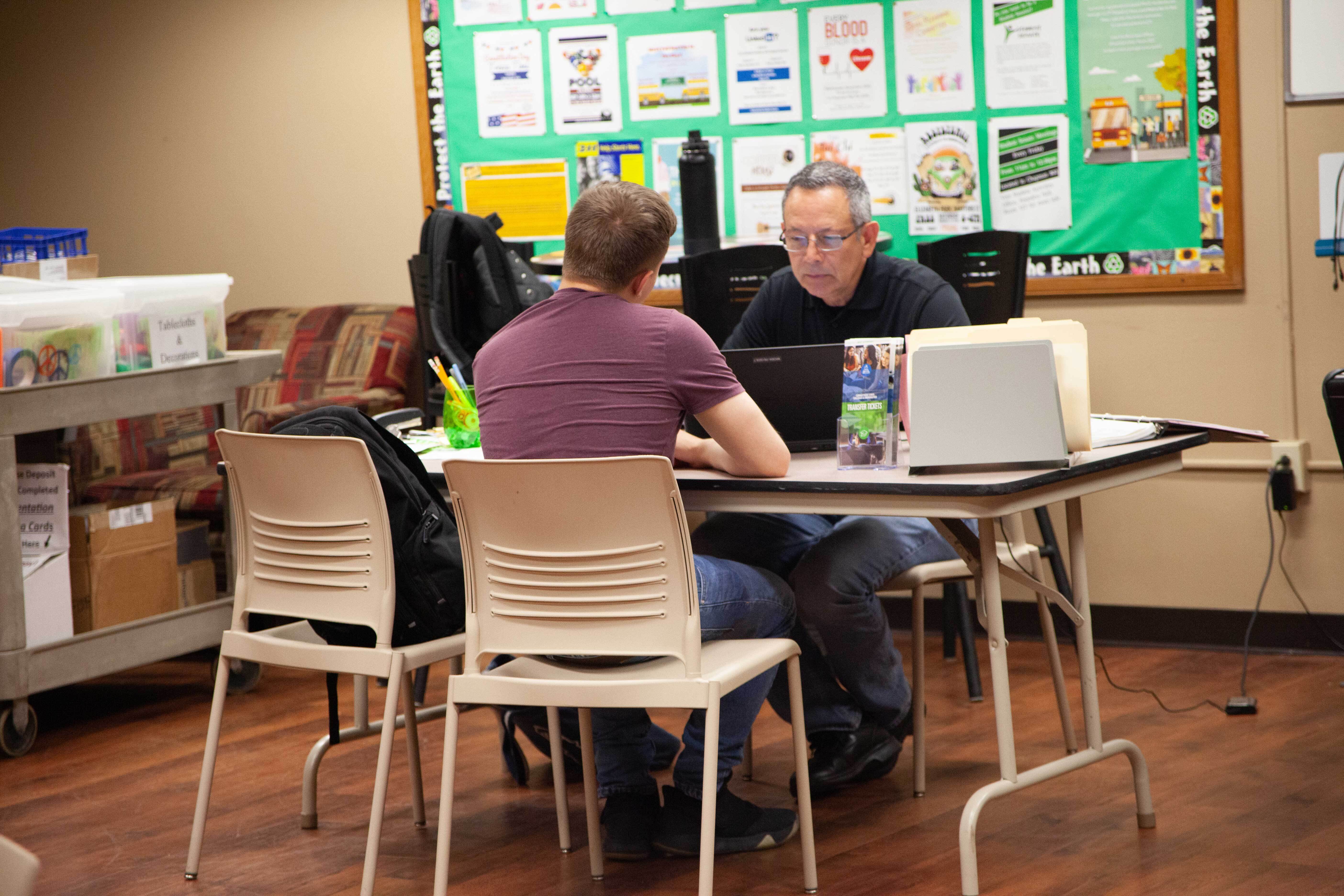 advisor and student talk over table to choose courses for upcoming semester