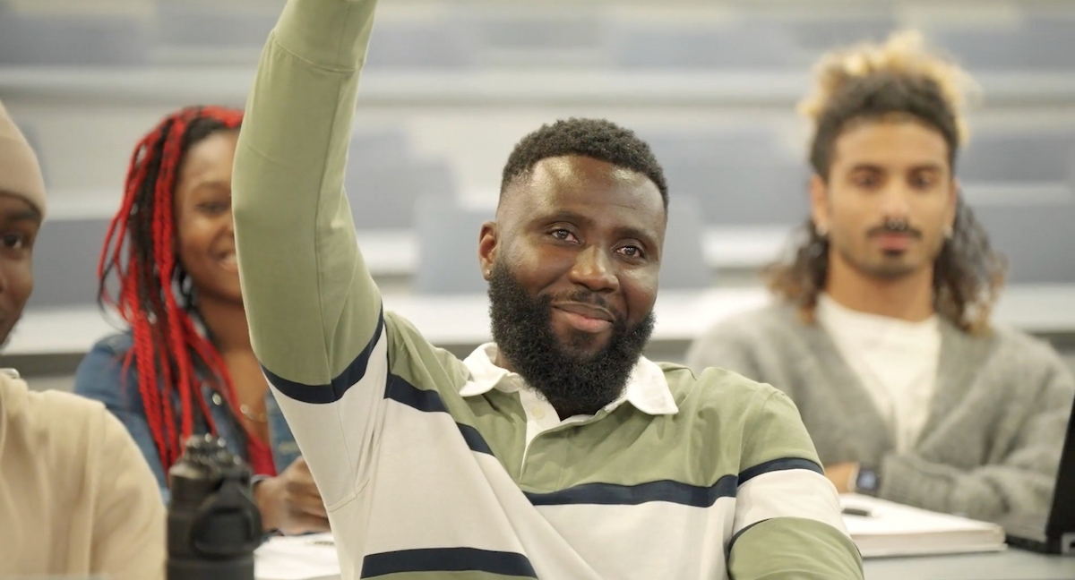 smiling student in class raises hand