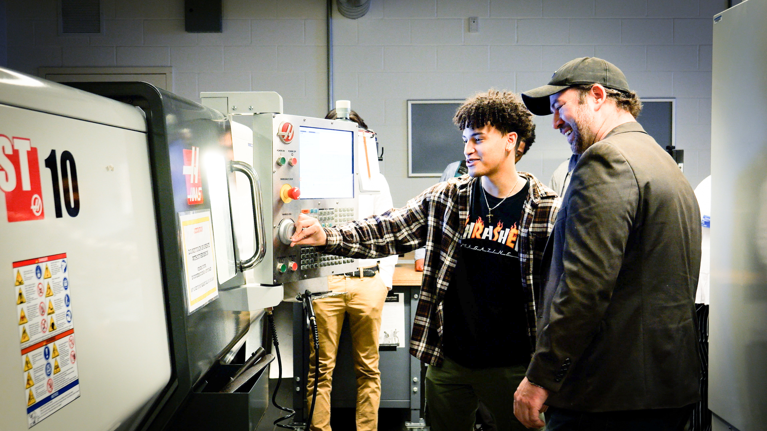 student looks at machine with professor