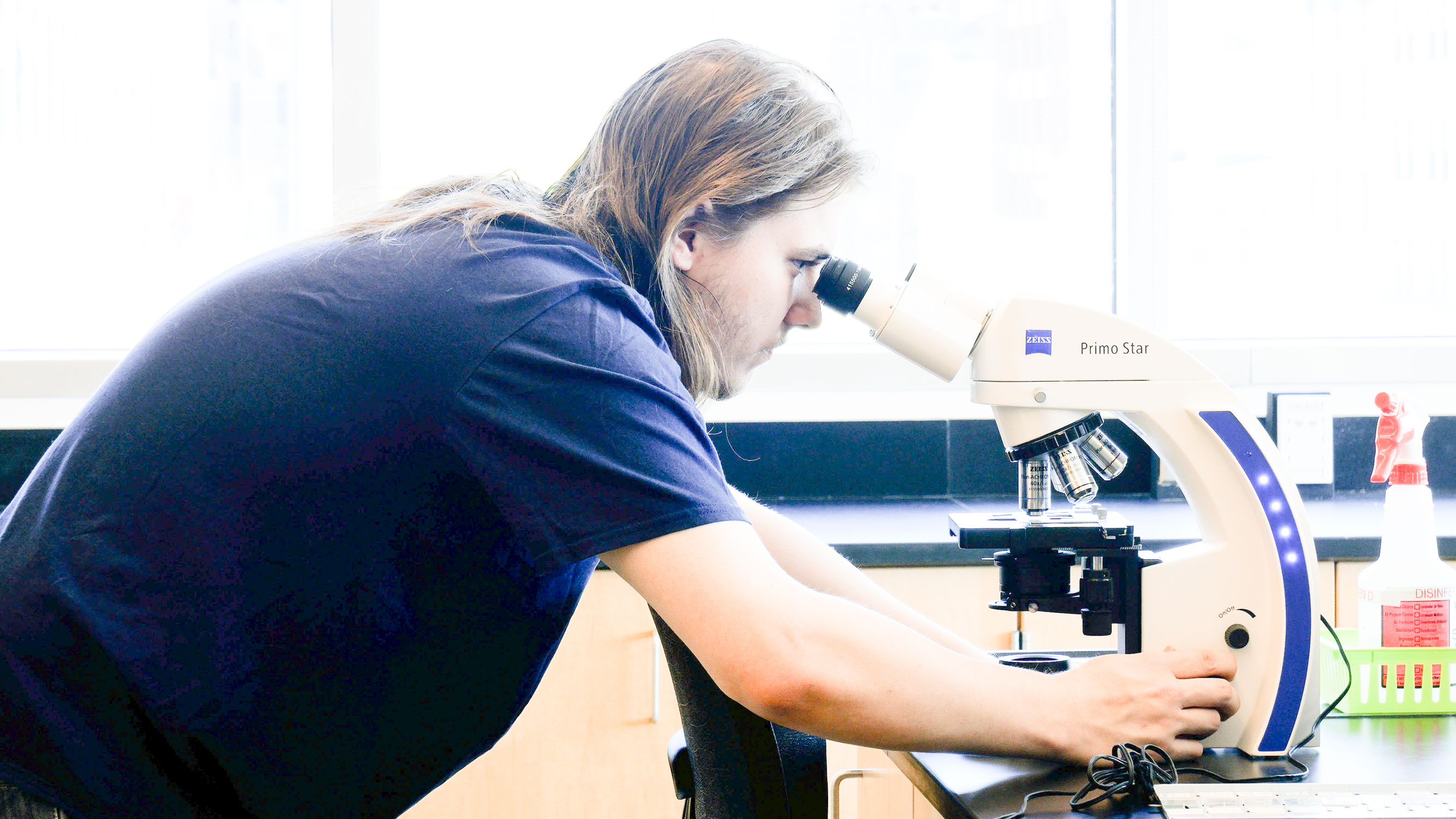 student looks through microsope