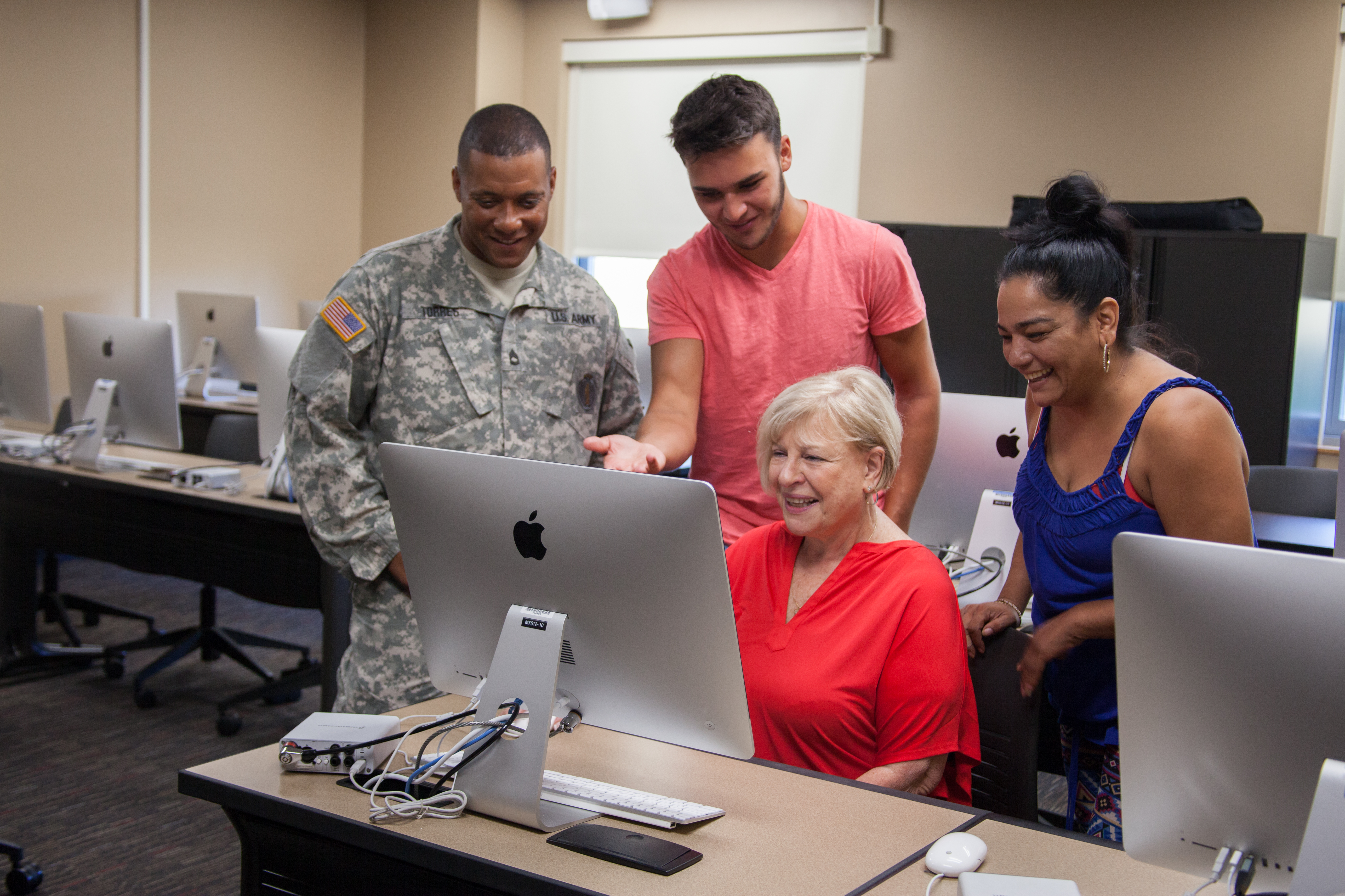 group of students look at large Macbook screen in computer lab