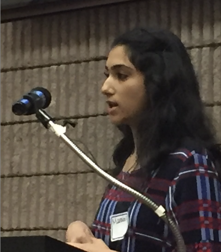 Manahil Khan speaks into microphone during academic convivium