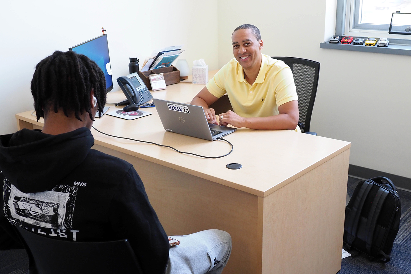 Advisor sits at desk facing student ready to help pick classes.