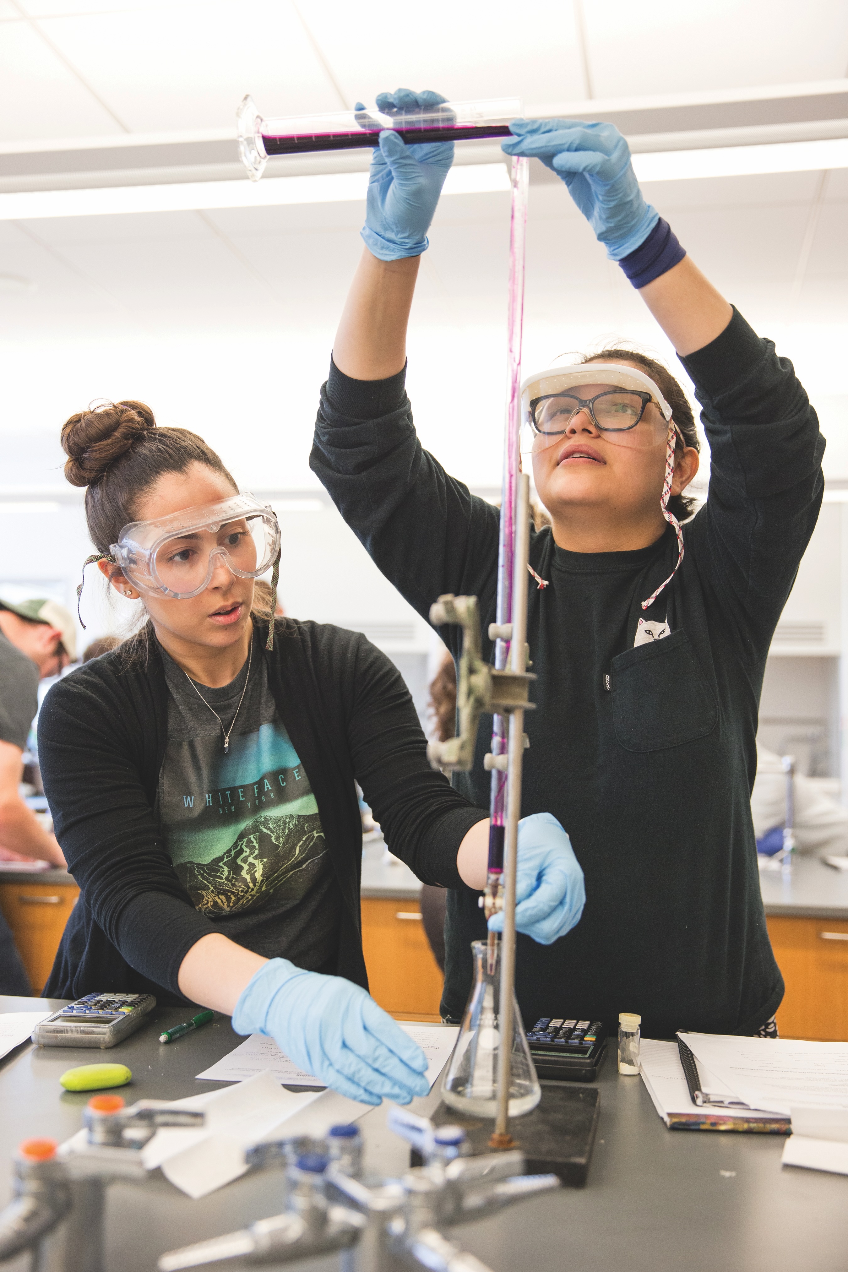 Two students fill beaker in science classroom.