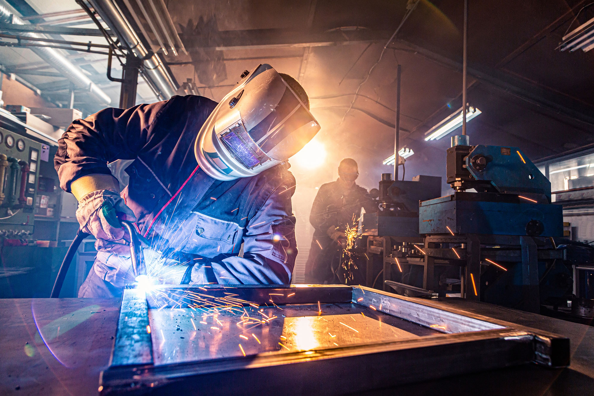 welder joins pieces while another welder works in background