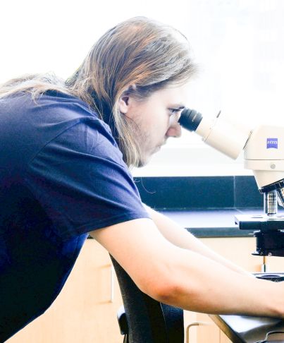 student looks through microscope
