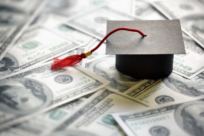 paper graduation atop $100 bills