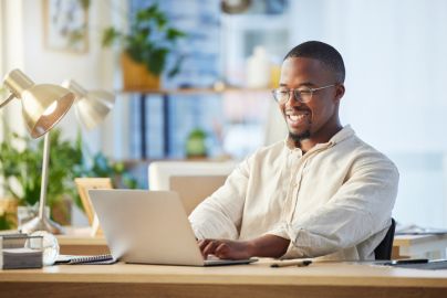 man smiles while working on his laptop