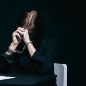 woman in handcuffs looks down with head in hands