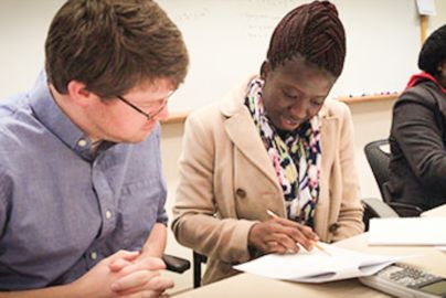 Two students look at paper together in classroom