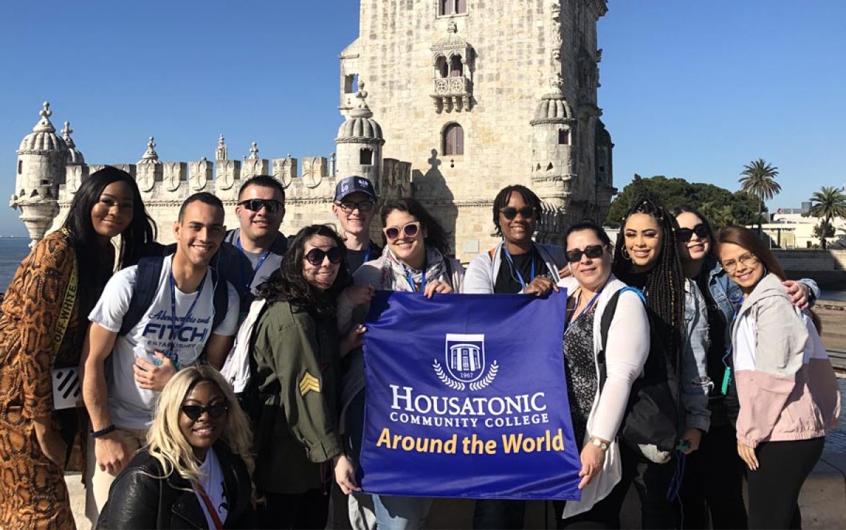 The Tower of Belem in Lisbon, Portugal, Spring 2019 with study abroad students holding Housatonic Flag in front of it