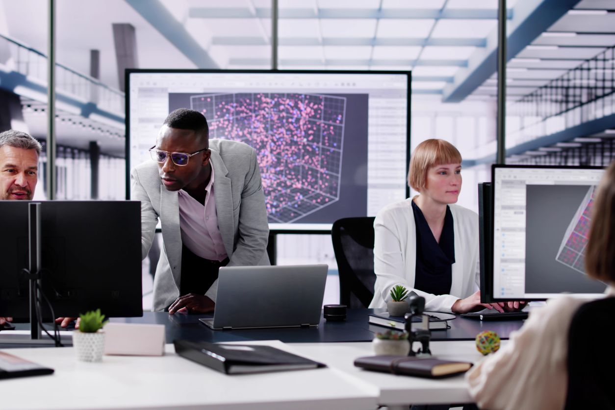 group of people in glass paneled office on computer screens working together