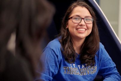 smiling student wearing CT State Three Rivers shirt