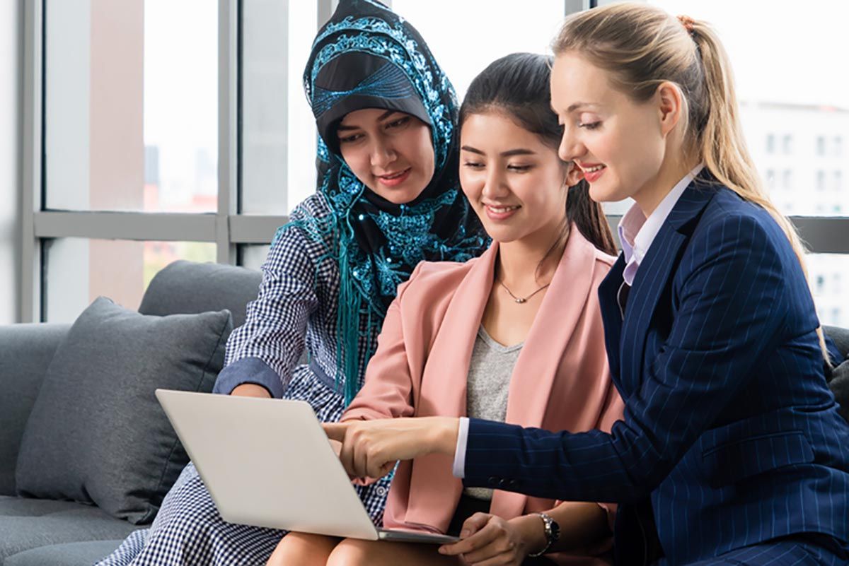 Three women pointing at information on a laptop