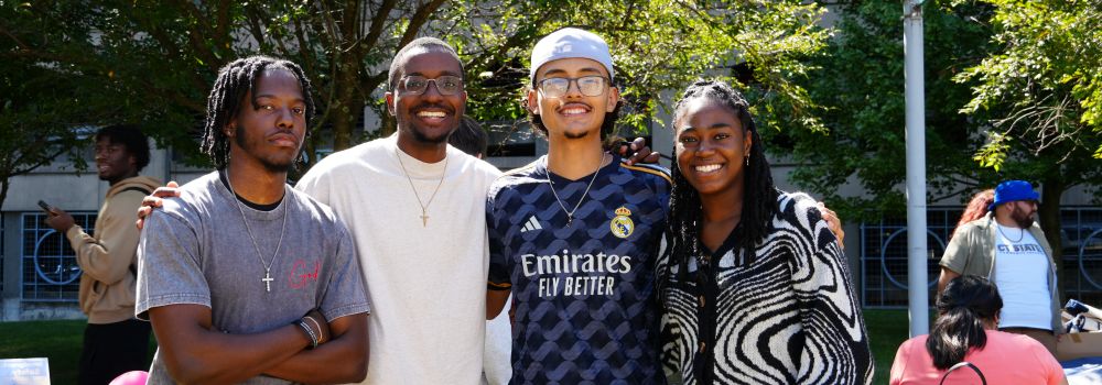 group of four students smile at camera