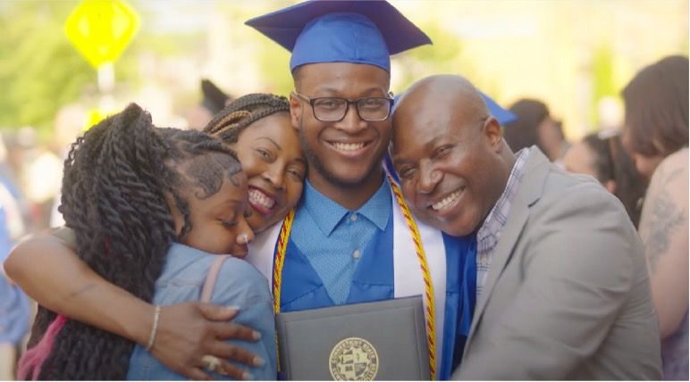 smiling graduate being hugged by family