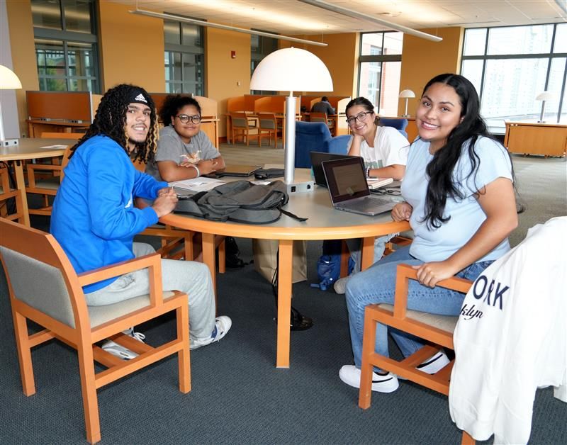 Group of students sit around table in Tunxis library.