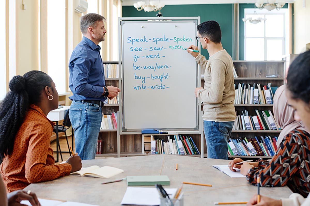 Teacher insturcting at white board in front of adult students