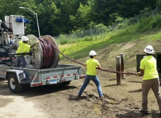 line workers pull line off truck.