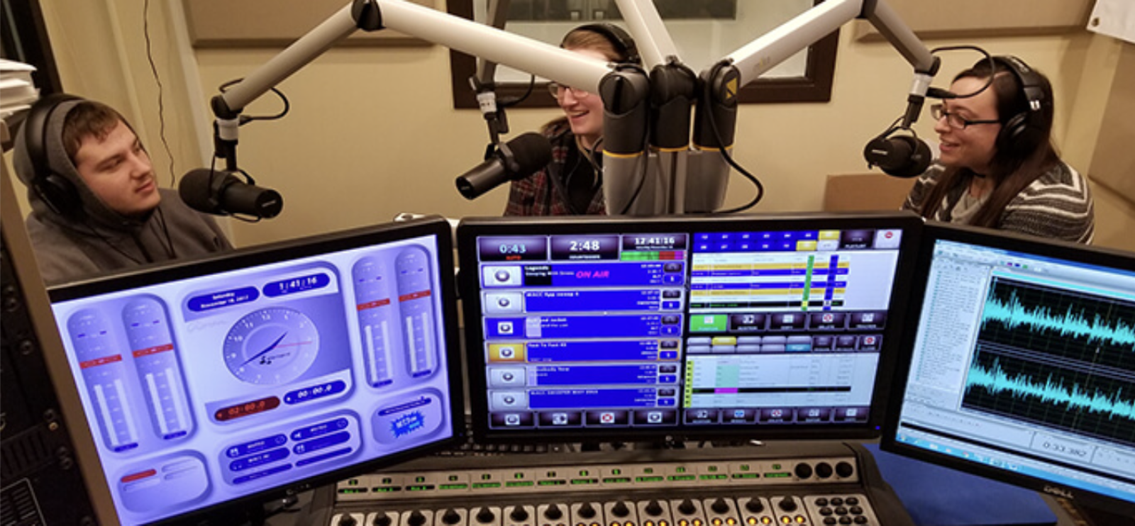 students talk on microphones in radio studio