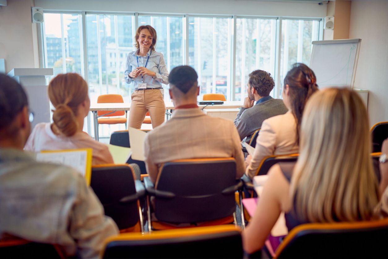 instructor smiles in front of group of business professional students