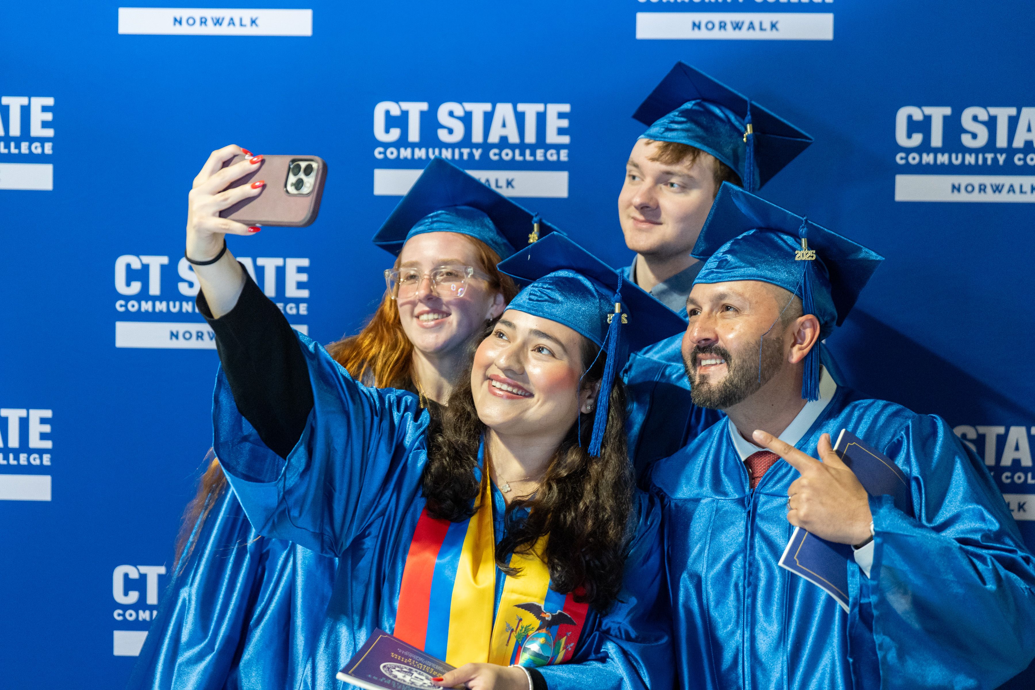 Group of students hold up cell phone for impromptu selfie.
