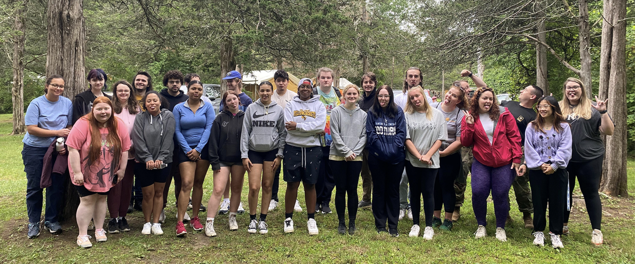 Large group of TSS students in woods pose in goofy ways at camera