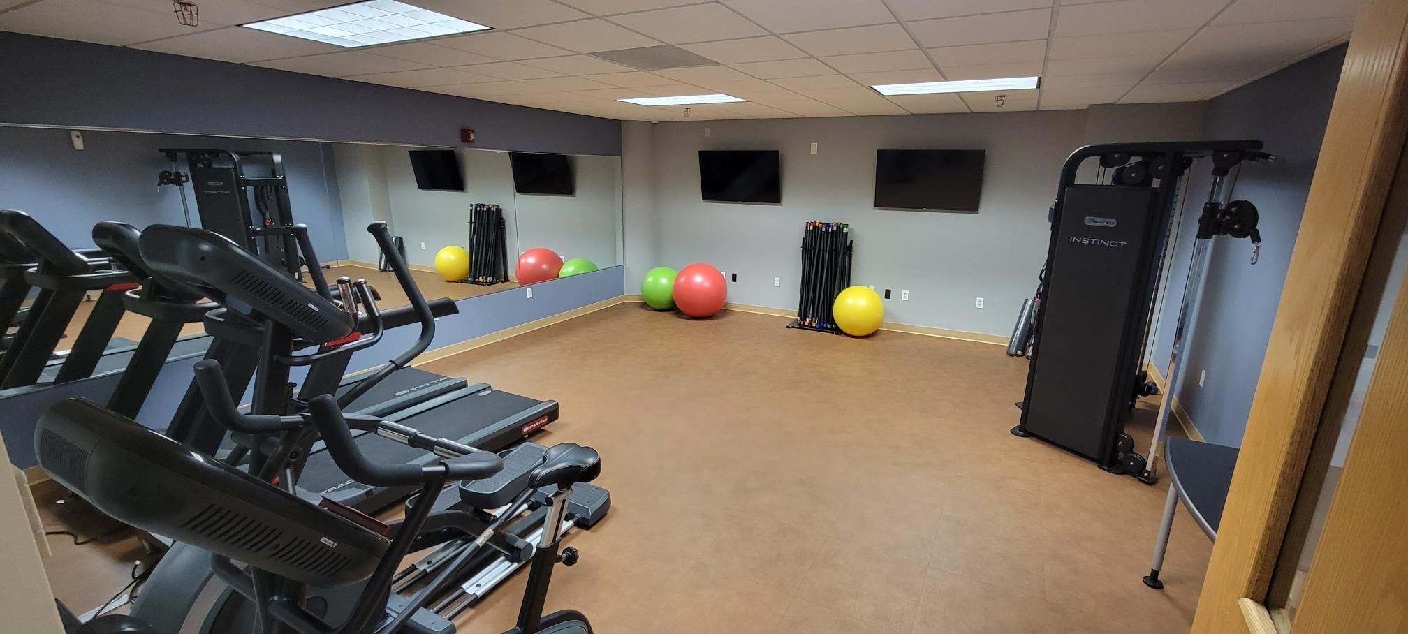 Capital Fitness Center is a room with treadmills, mirrored walls, elliptical, bike and more.