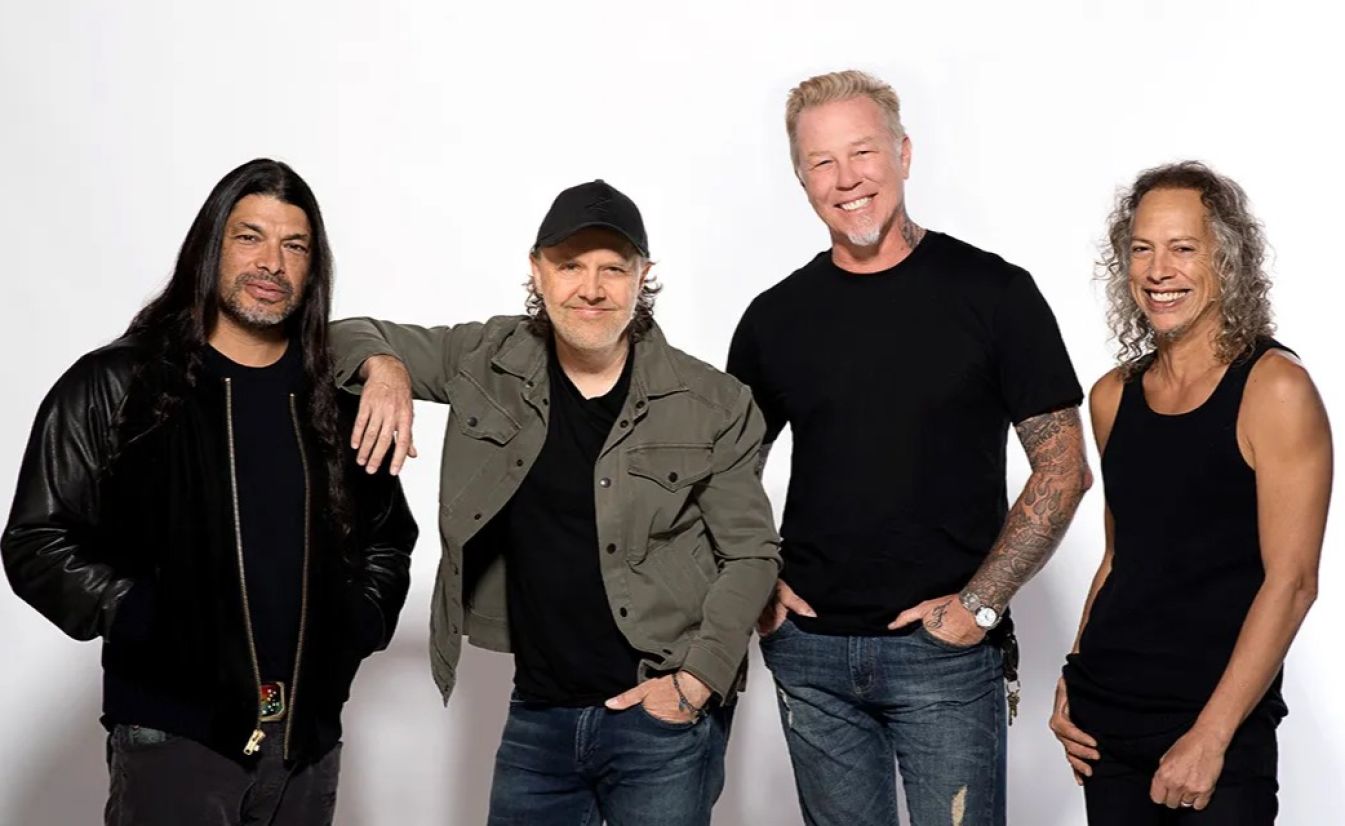 Members of Metallica stand together and smile.