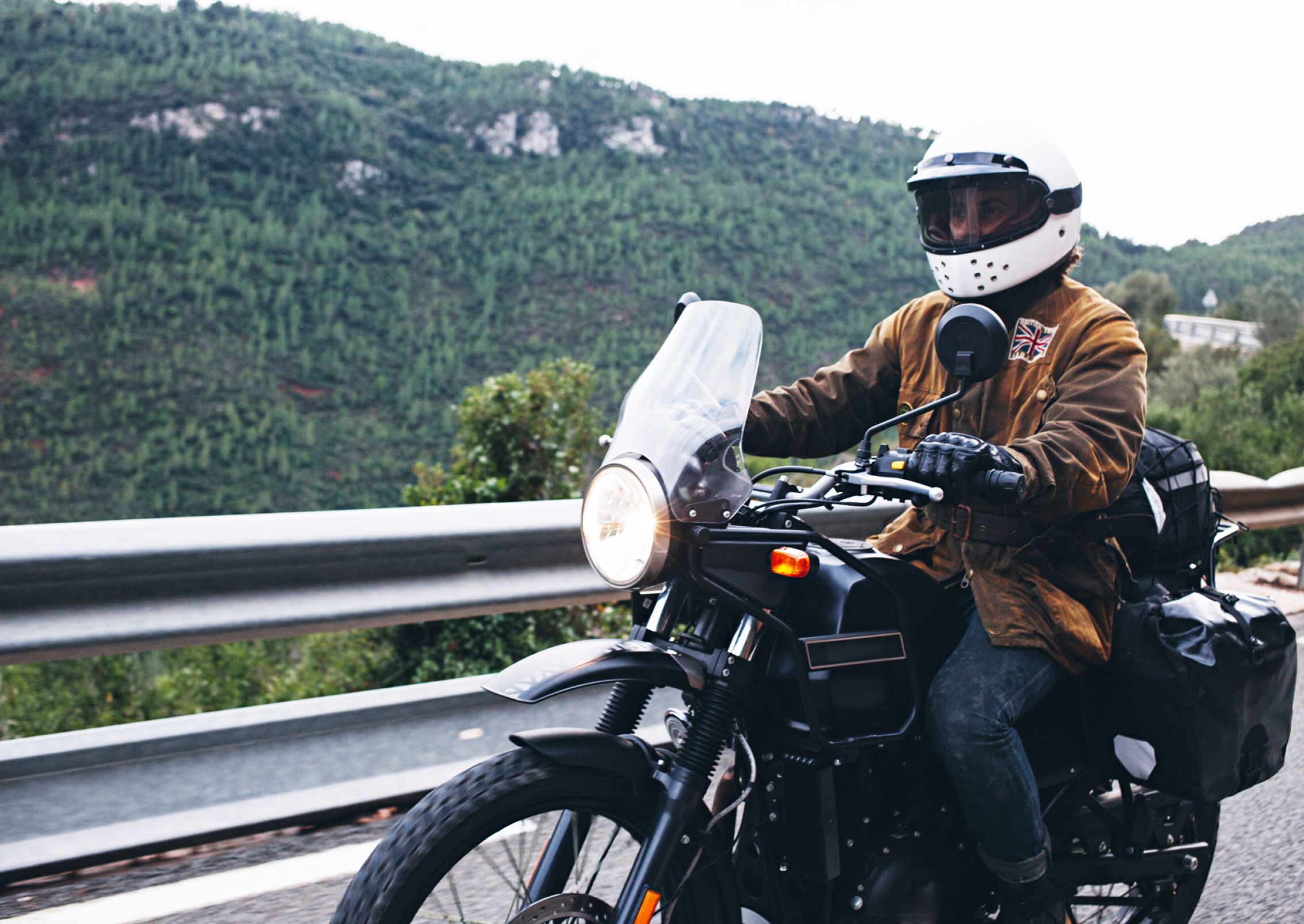 Rider on motorcycle drives in front of mountain.
