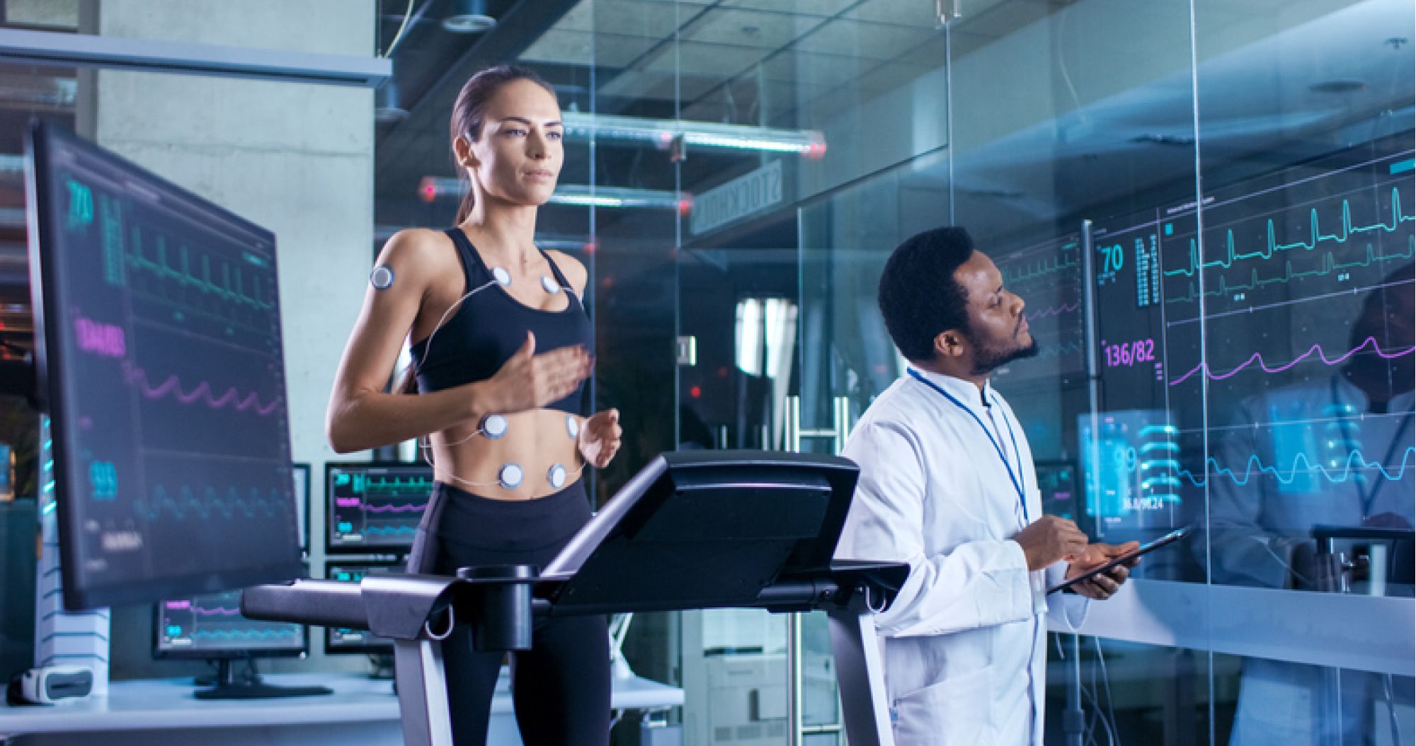 woman runs on treadmill connected to monitors being tracked by doctor