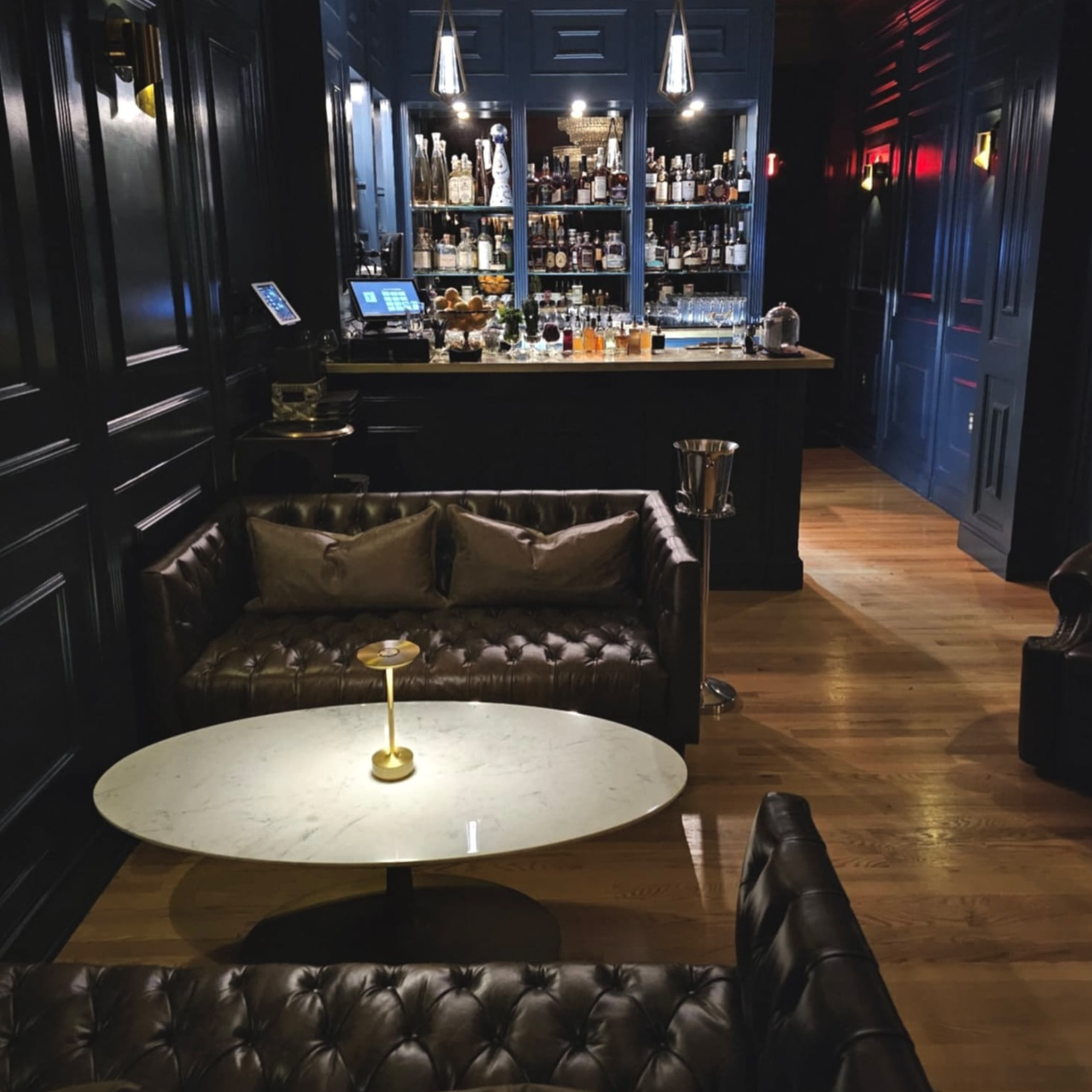 Interior of Franklin lounge featuring a bar in the background and table and couches in foreground along with low mood lighting.