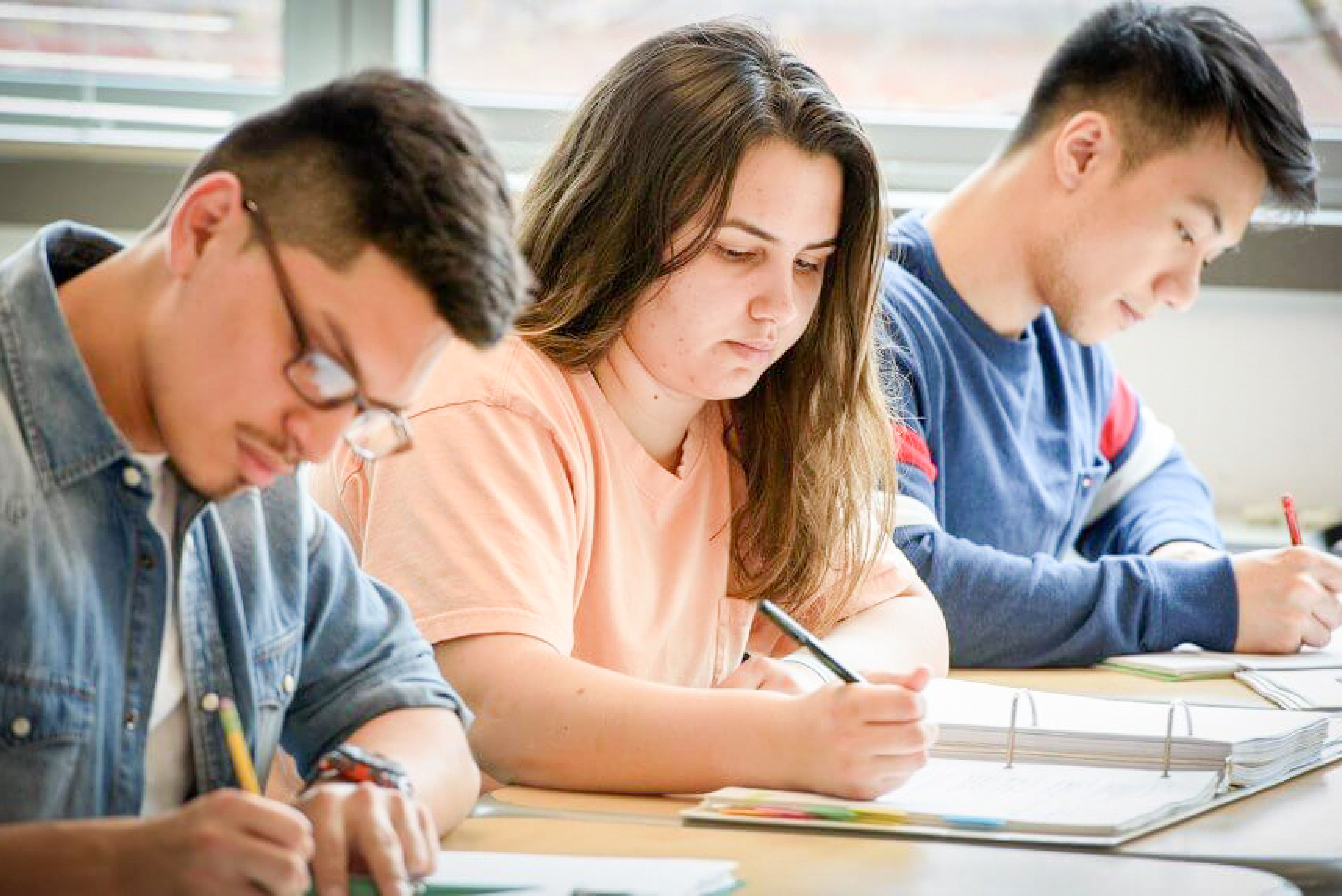 Students sit at table together with books talking